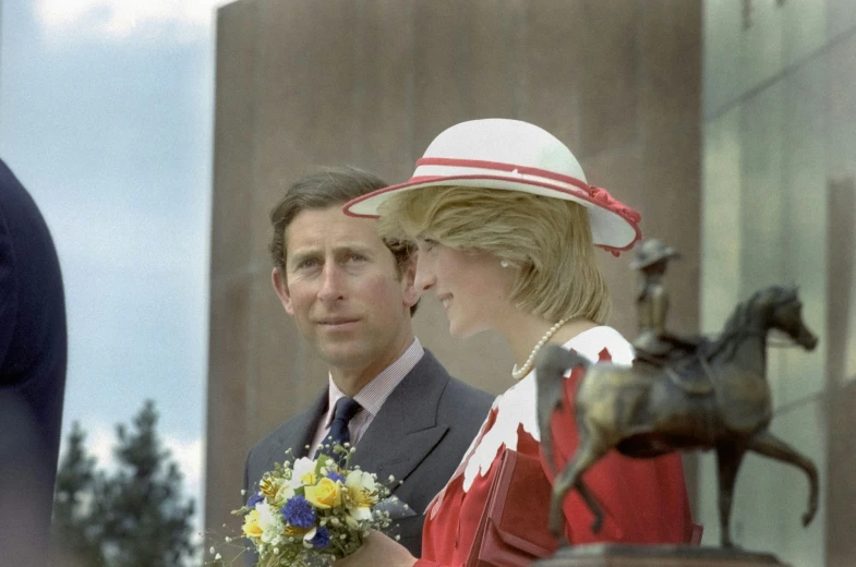 two people standing near one another with a statue in the background