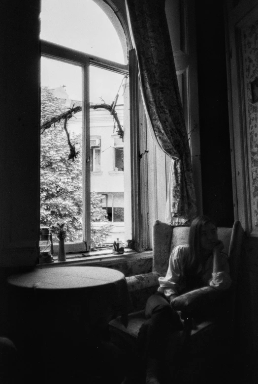 a person sitting in front of a window with a table and chair