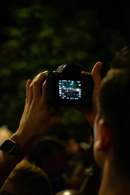 a person holding up a camera in a darkened area