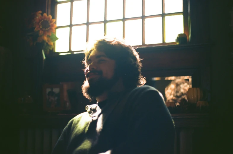 a man with long hair sitting in front of a window