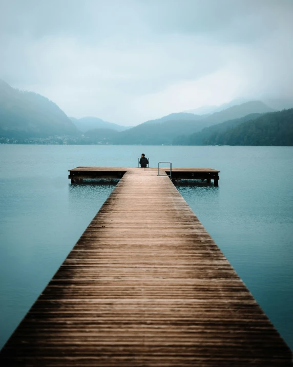 two people sitting on top of a wooden dock