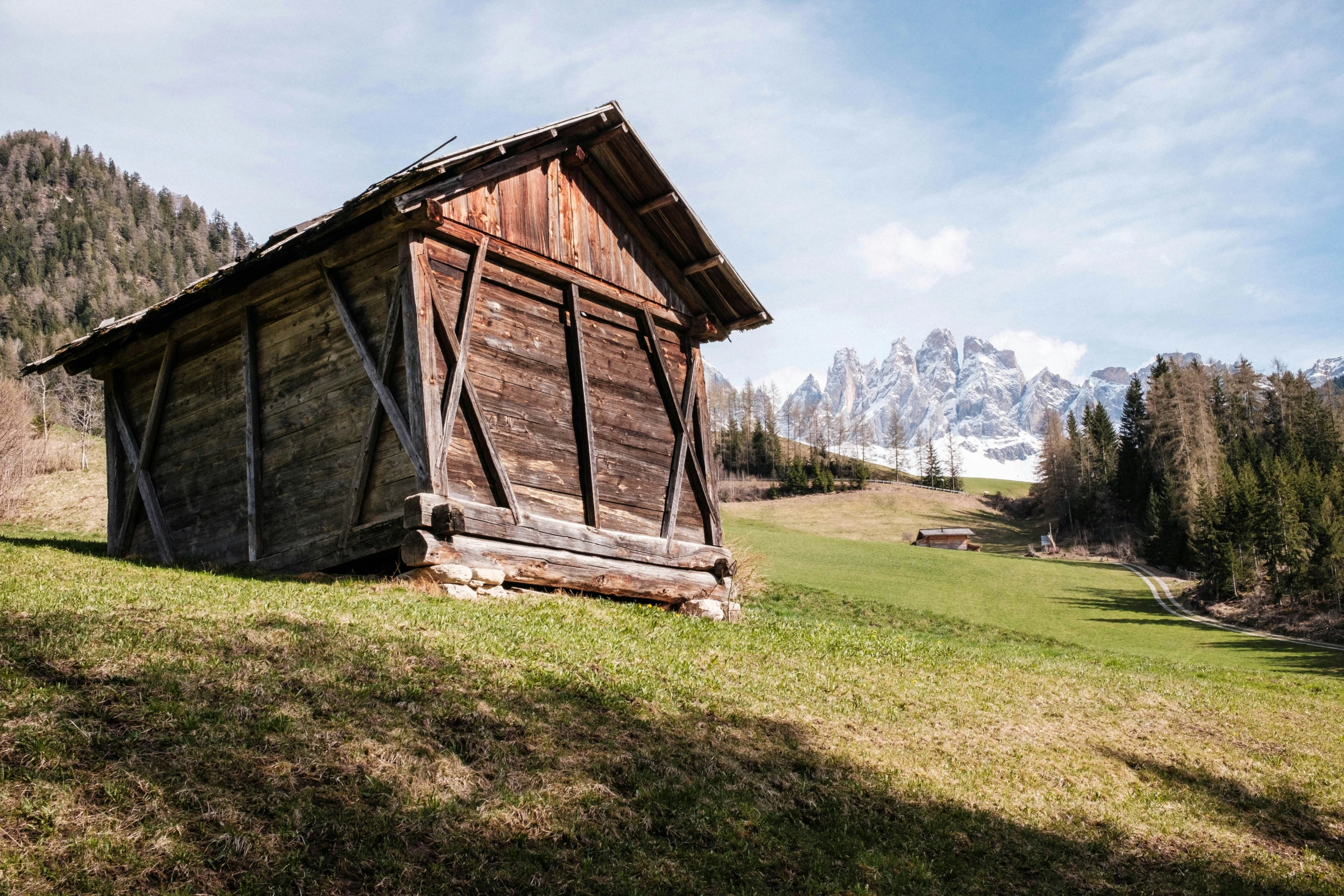 an old barn in a pasture with mountains and trees behind it