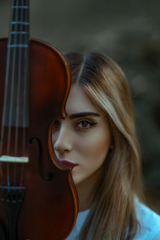 the young woman is holding her violin in front of her face