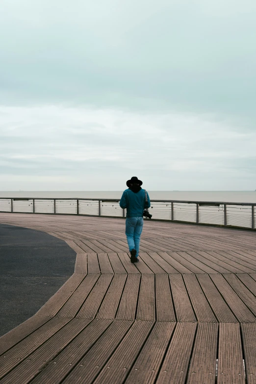 a man in winter clothing is walking along the boardwalk