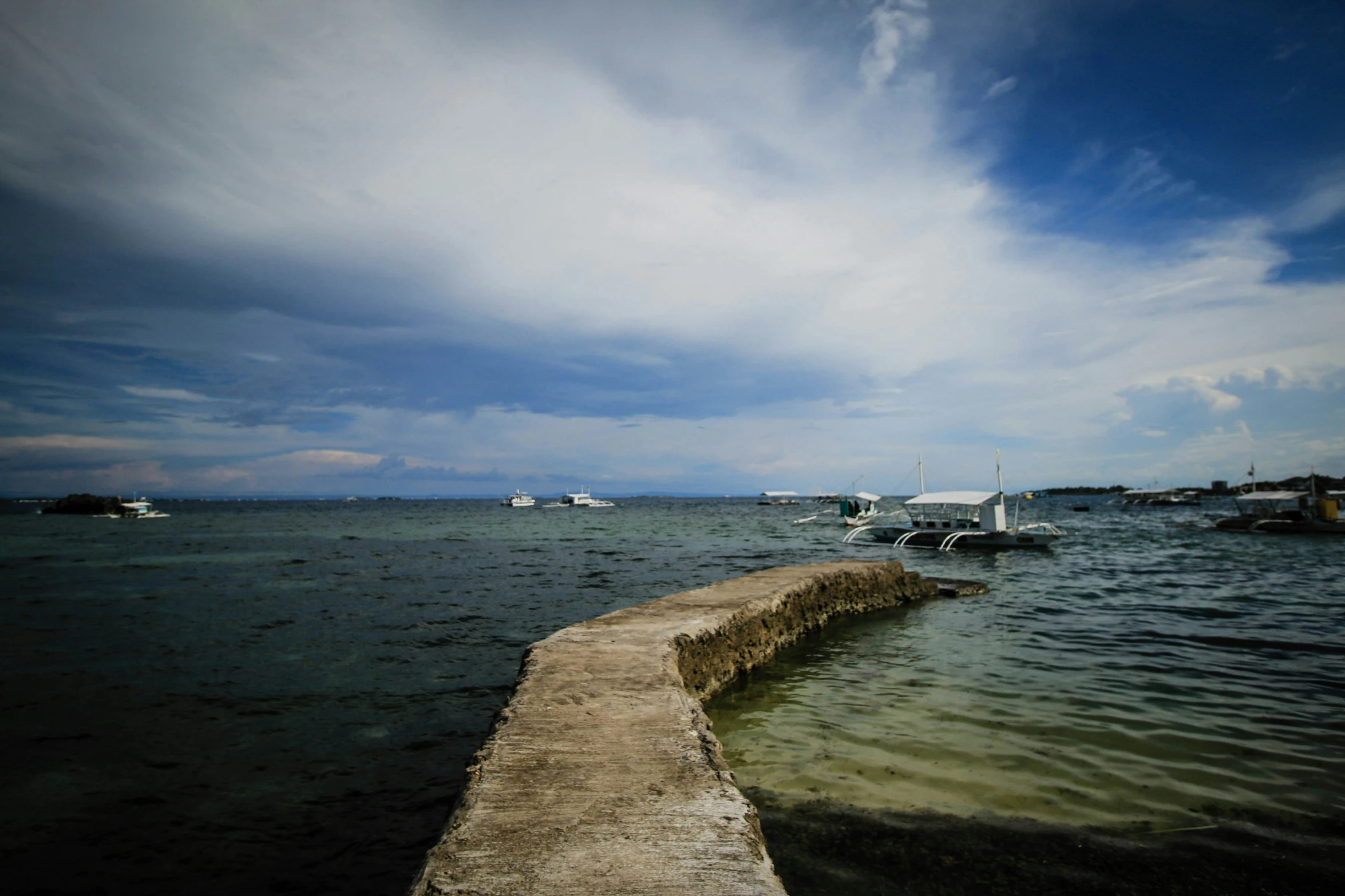 a pier with several boats in the ocean