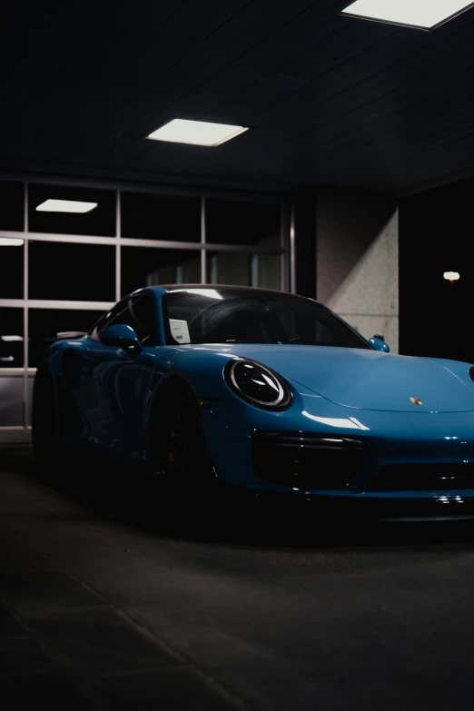 a blue porsche car in front of a garage door