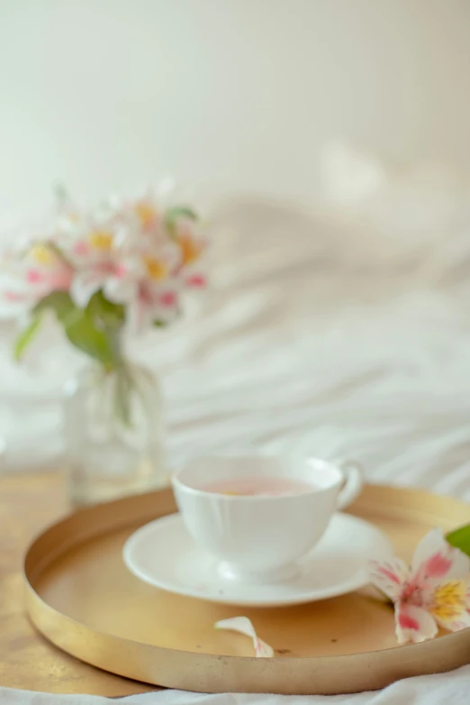 a cup and saucer set on a tray on top of a bed