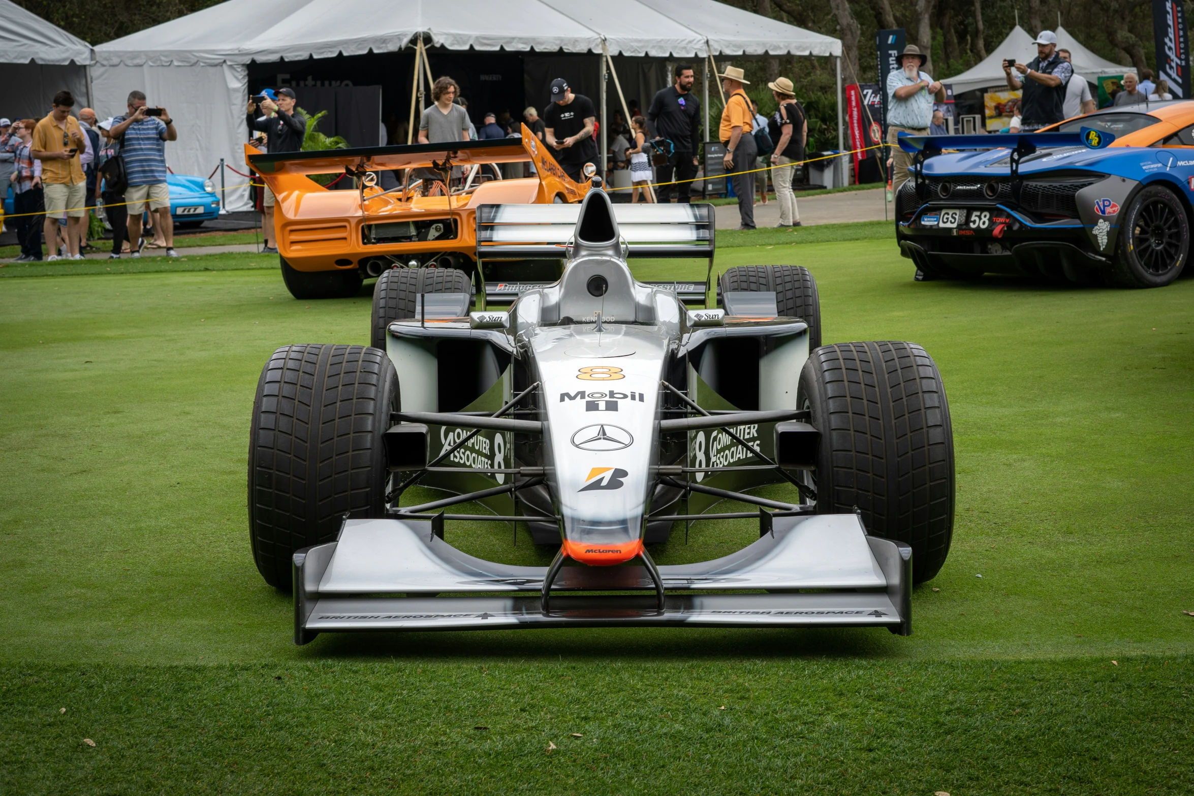 several classic race cars are parked near a tent