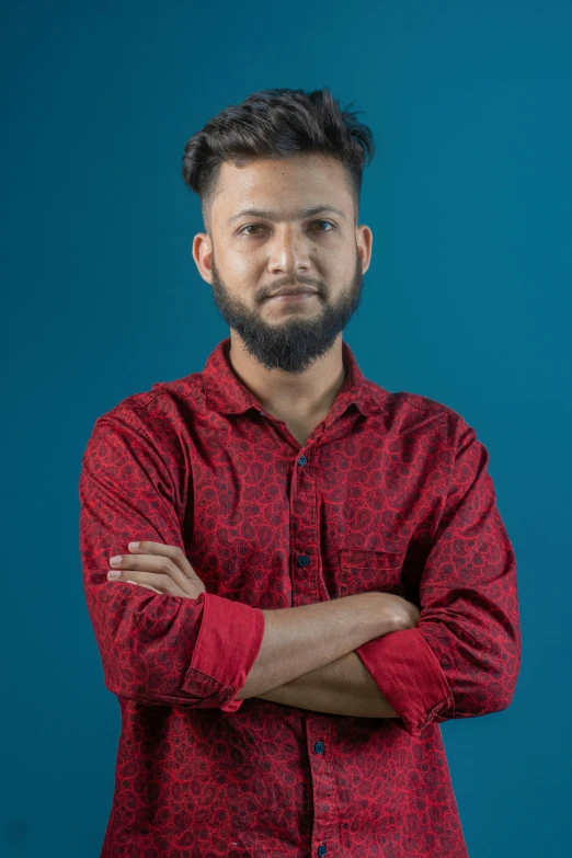 a man with a beard stands with his arms crossed