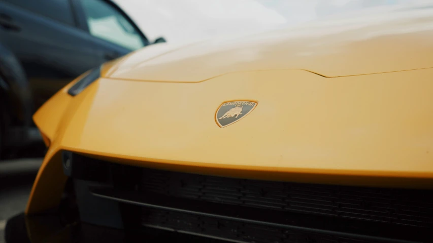 the front of a yellow lamb car parked next to another black car