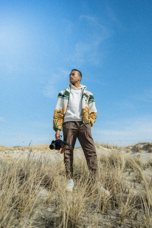 a man wearing a jacket is standing in some tall grass