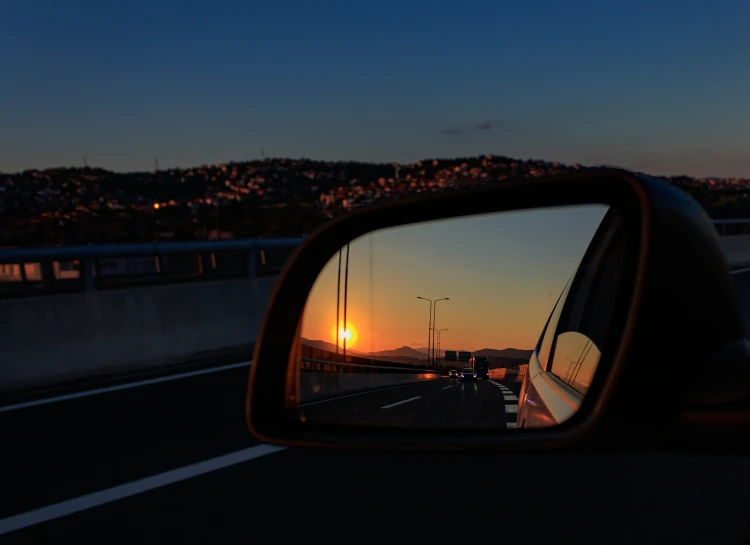 a sunset through the side mirror of a vehicle