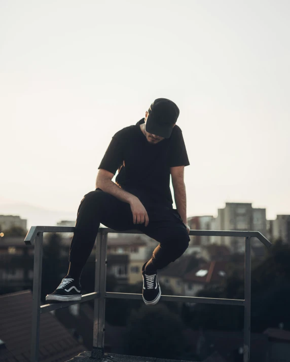 a man sitting on the top of a railing with his skateboard