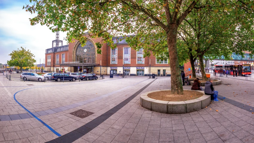 a person is sitting next to the tree on a square