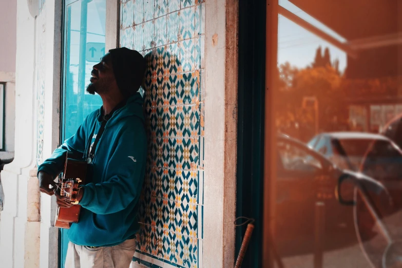 a man leaning on the side of a window holding onto a cup