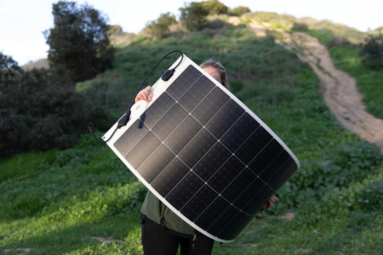 a man carrying a black and white solar panel to the side