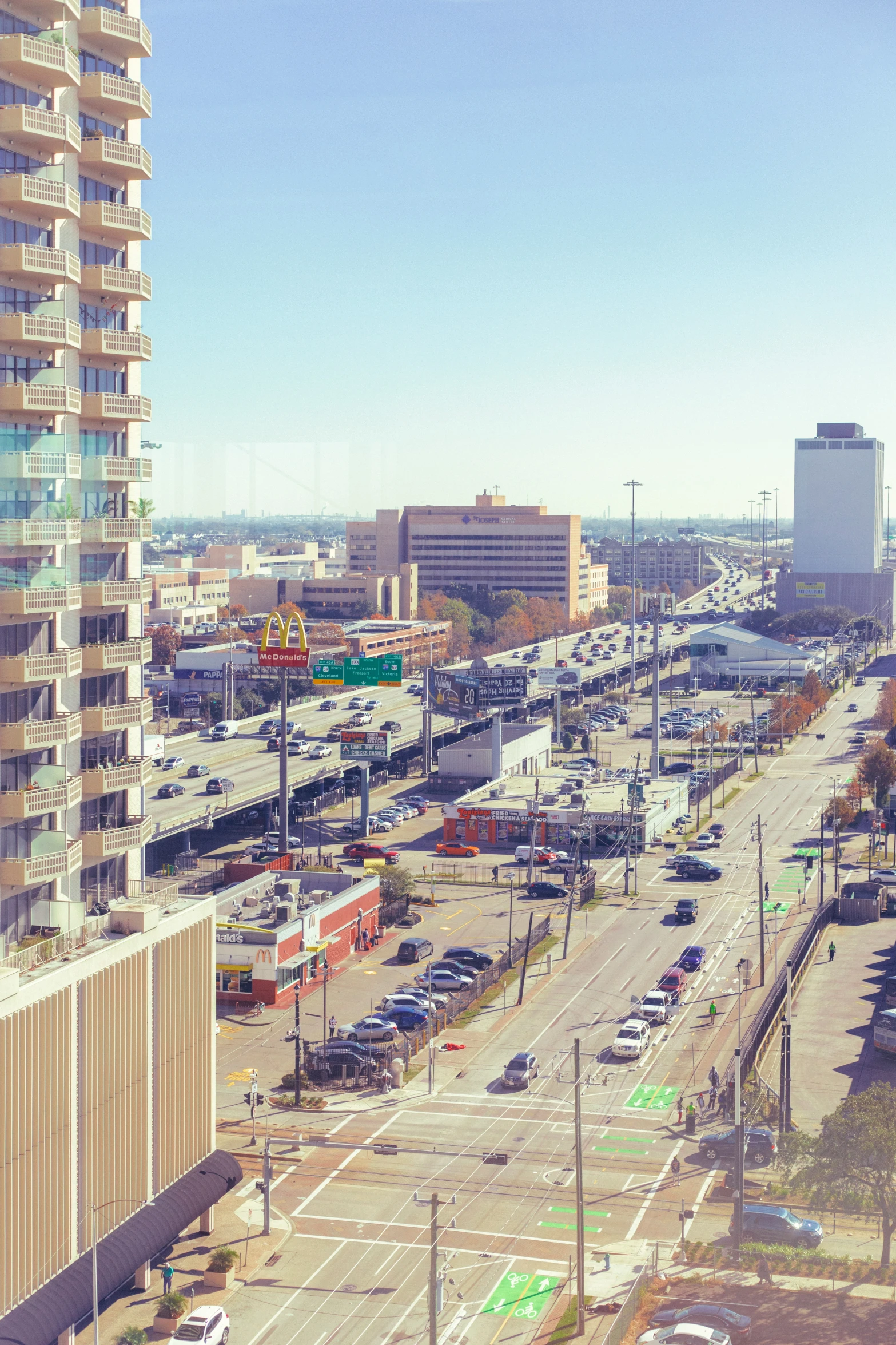 an empty parking lot and an empty parking lot with lots of parked cars in front of a tall building