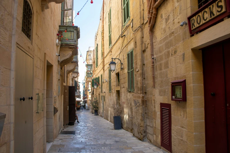 a narrow stone paved alley with shuttered red doors