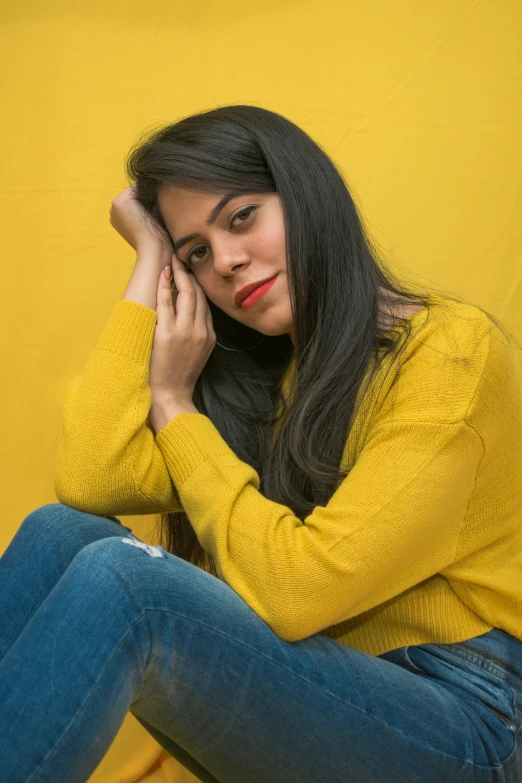 a woman in yellow sitting with her hands on her head