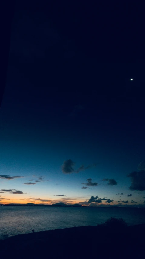 silhouette of sea at sunset, including the moon