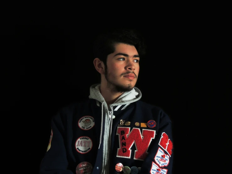 a man poses in his hooded jacket with an ugly name tag