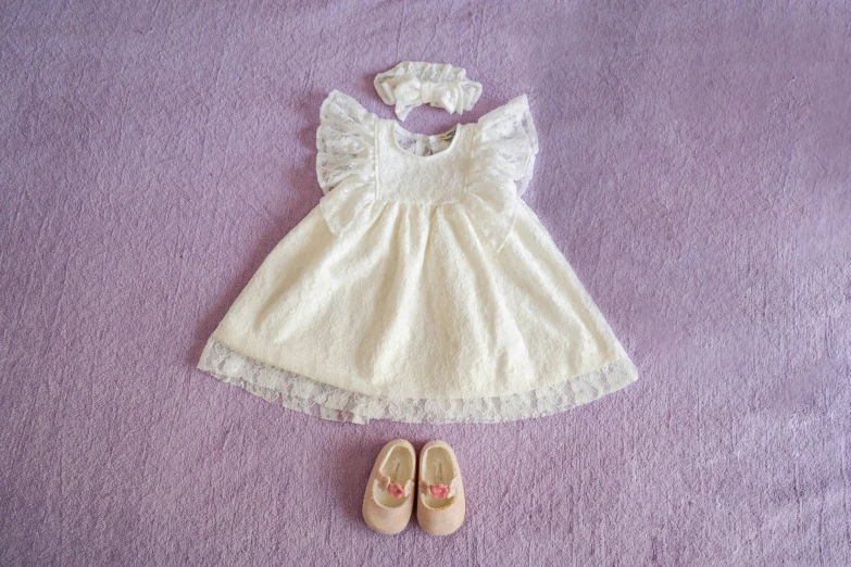 a baby's dress and shoes on purple blankets