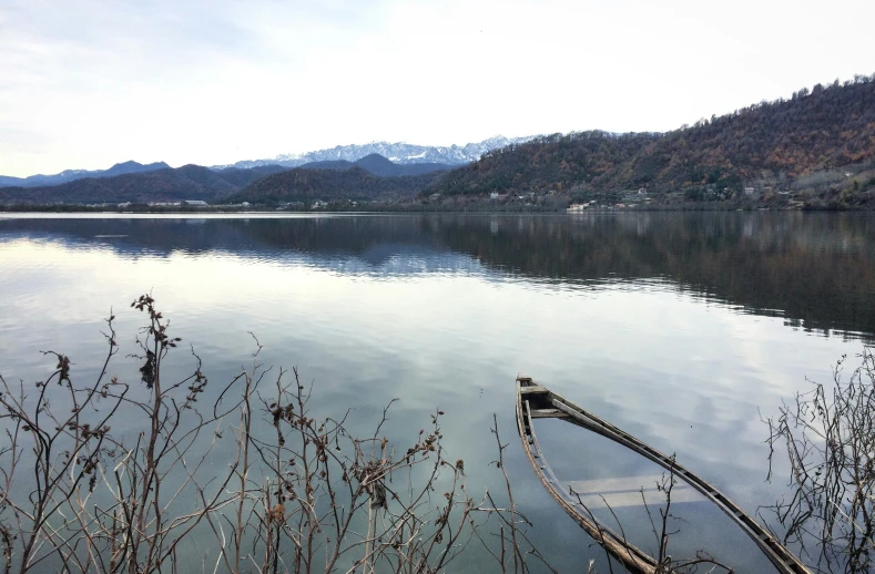 a lone boat docked on the edge of a large lake