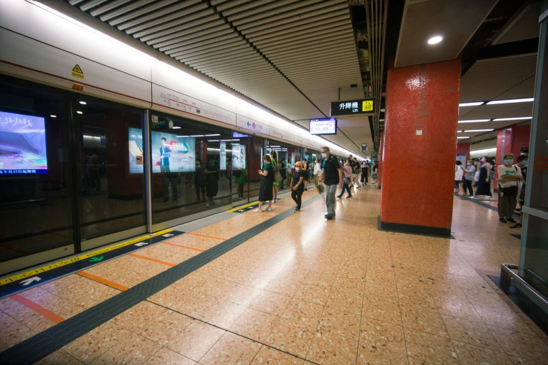 a large group of people walking around inside of a train station