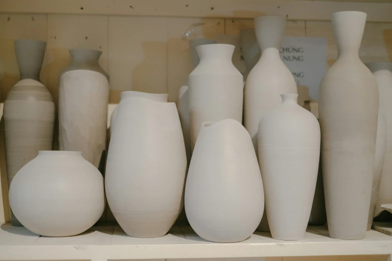 a shelf with various white vases on it