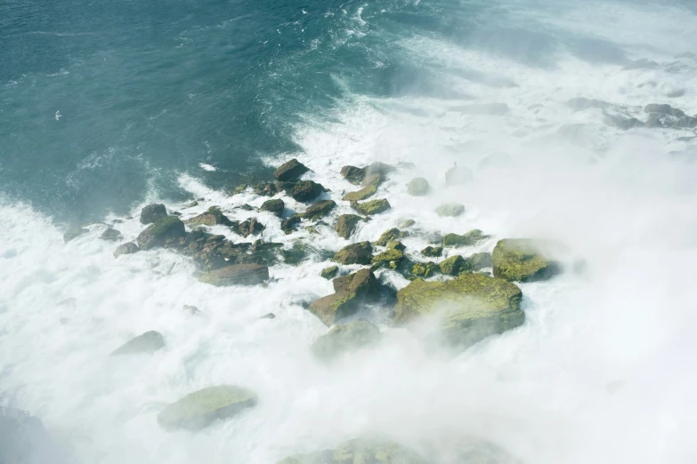 waves splash over rocks and seaweed as they break on the coast