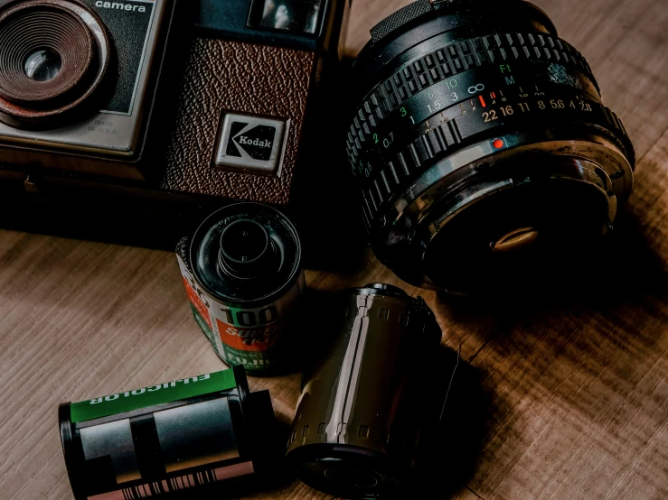 an old camera with three lens covers, and some batteries sitting beside it