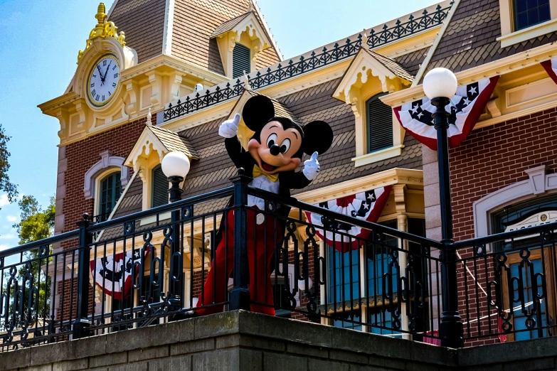 a mickey mouse figure is on the railing outside of the disneyland world clock