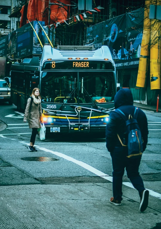 two people walking along the sidewalk while a bus is going by