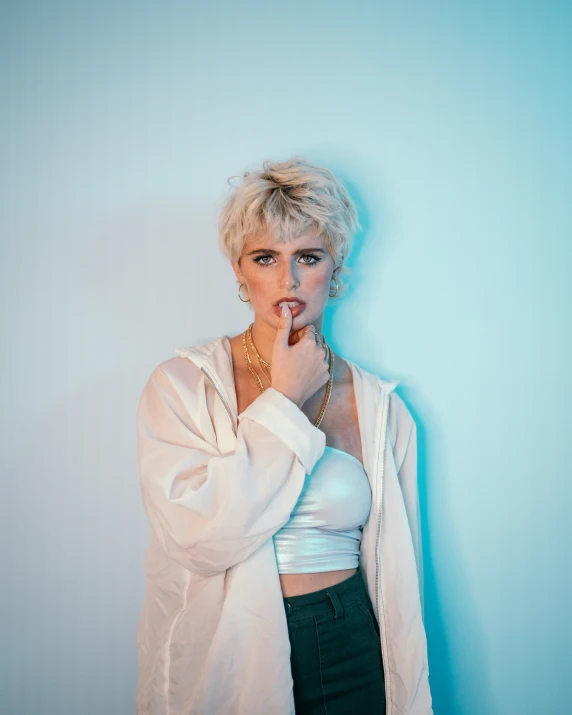 a woman standing next to a wall with a cigarette in her mouth