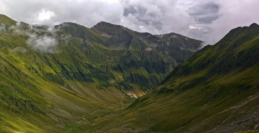 a valley surrounded by mountains under a cloudy sky