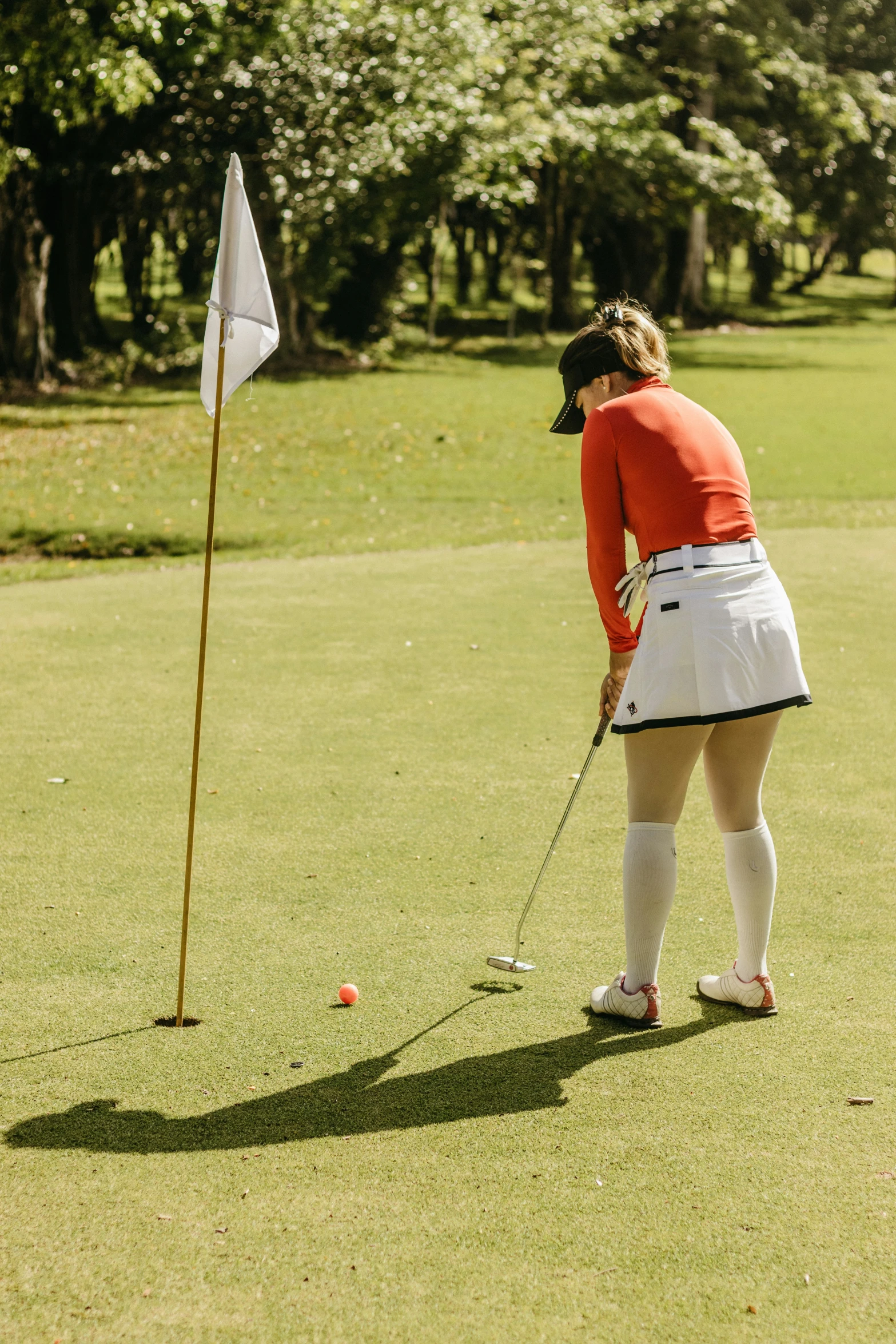 a woman that is standing in the grass with a golf club