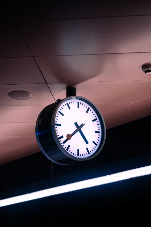 a clock is hanging from the ceiling above a sign