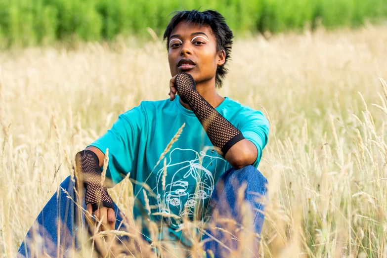 a woman sitting in tall grass, with a hand on her face