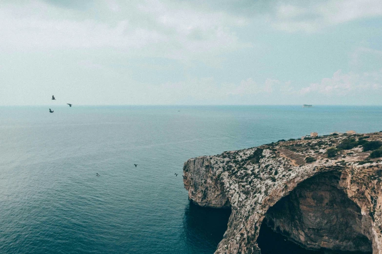 a scenic view of water and rocks with birds flying