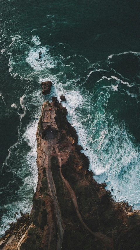 view from high down looking down over a rocky shoreline and crashing waves