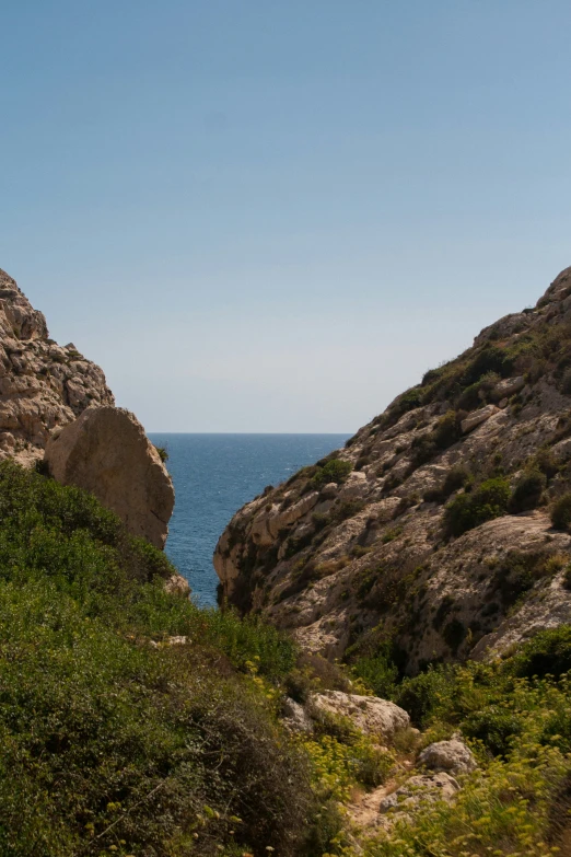 a road between two rocks with an ocean in the background