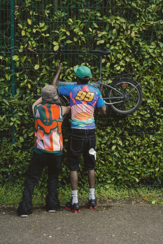 two people standing next to each other near a bush