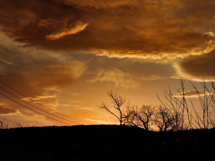 a cloud filled sky with telephone wires and telephone poles