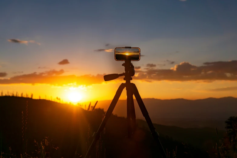 a camera is sitting on a tripod as the sun rises