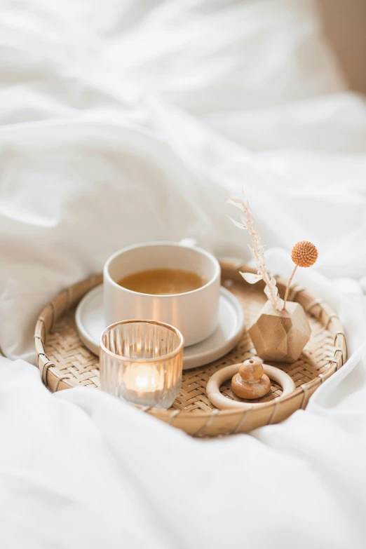 tea and candle on the bed with white linens