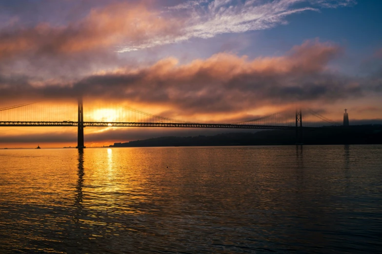 the sky is reflecting off the water and the bridge above it