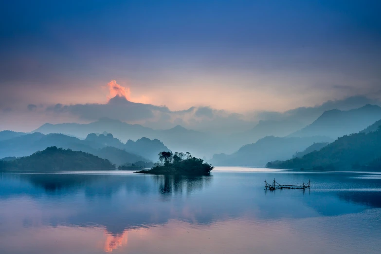 a mountain in the background has mist over the lake