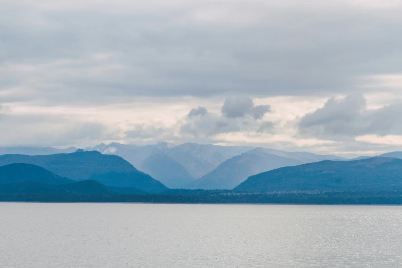 a lone boat out on the water near some mountains