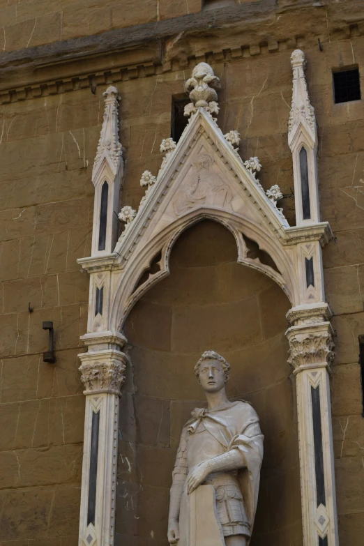 a statue standing in front of a tall building