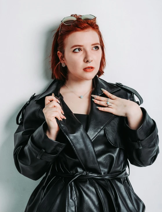 a woman in a black leather coat, with her hands on her chest